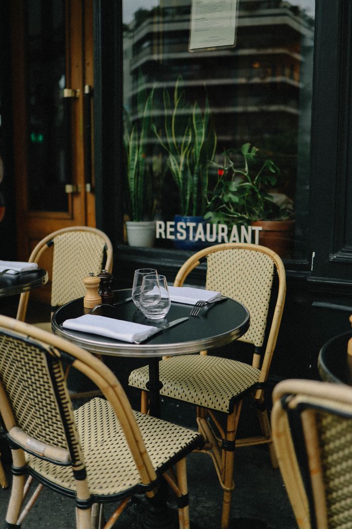 Charming outdoor restaurant setting with wicker chairs and tableware, ideal for al fresco dining.