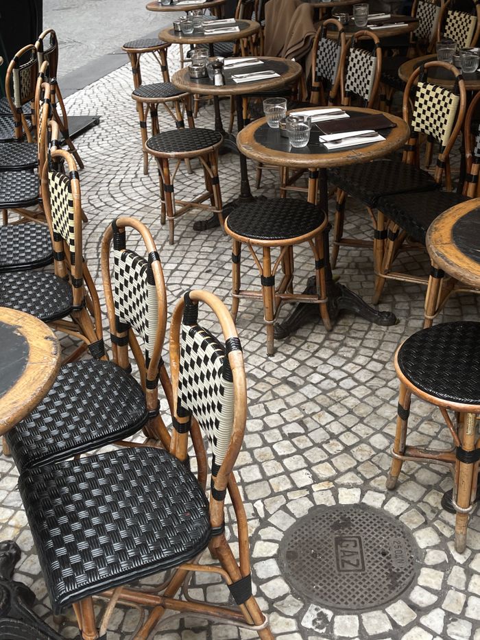 An inviting outdoor café with wicker chairs and tables on a cobblestone street.