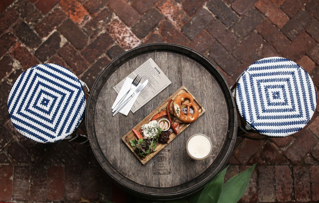 Overhead shot of a rustic meal setting on a wooden table with a pretzel dish and menus.